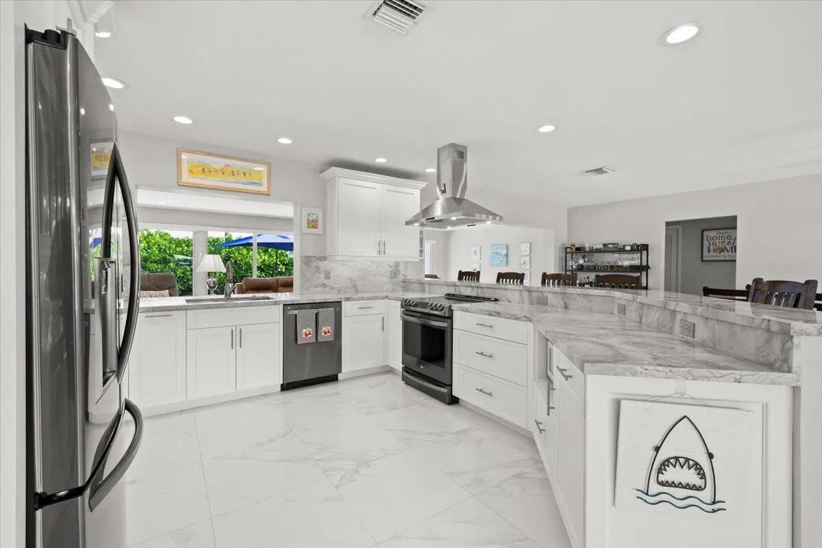 Expansive kitchen featuring white cabinetry, light-toned stone countertops, and a large curved island
