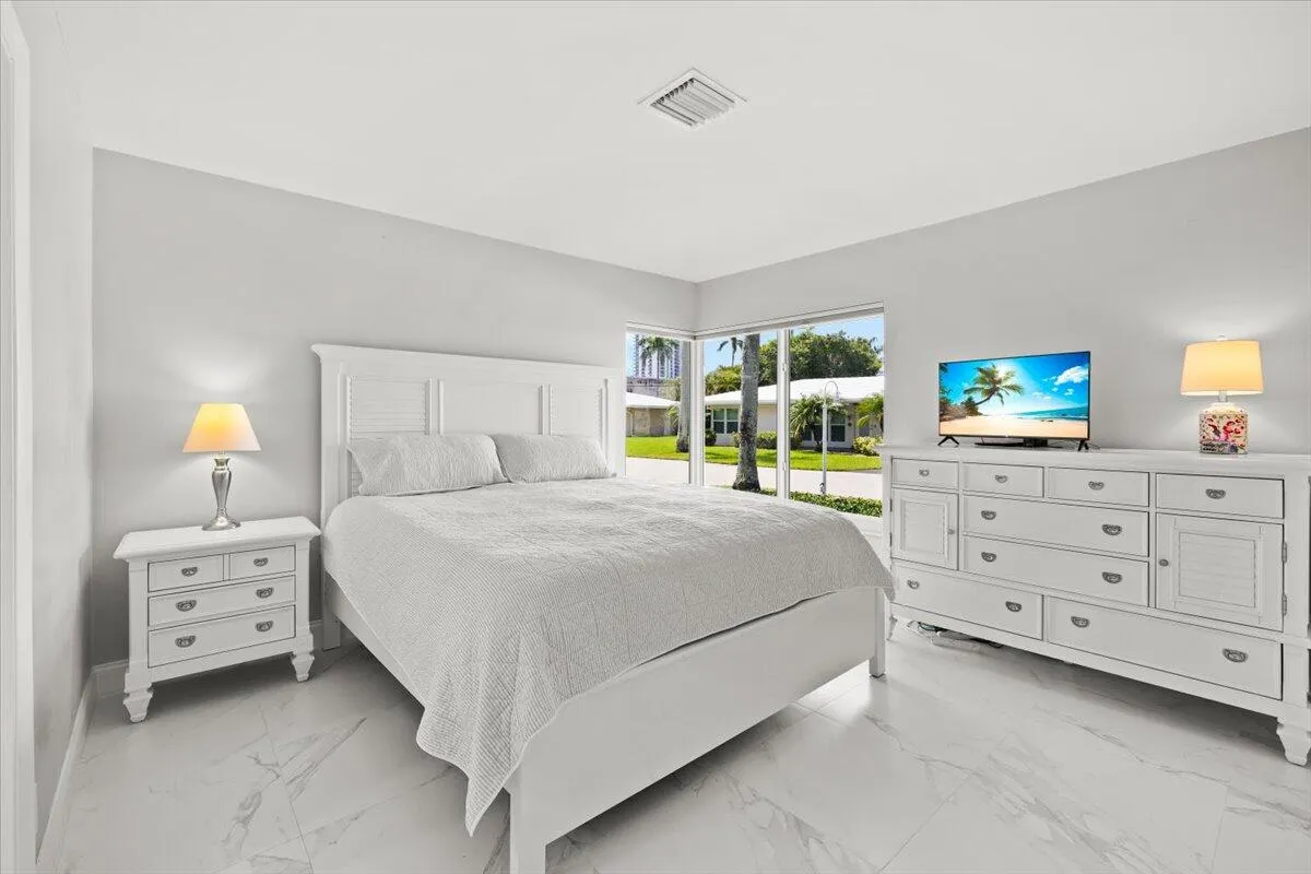 Spacious room featuring large windows, light gray wall tones, and white marble-look flooring