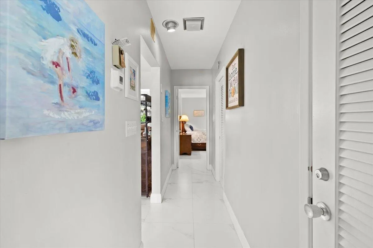 Hallway featuring recessed lighting, light-colored walls, white baseboards, and white tile flooring