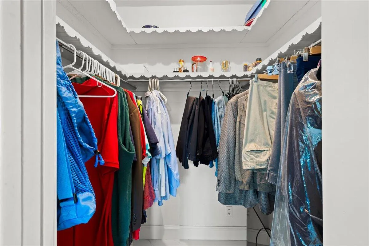 Built-in closet with scalloped trim shelving and white painted walls