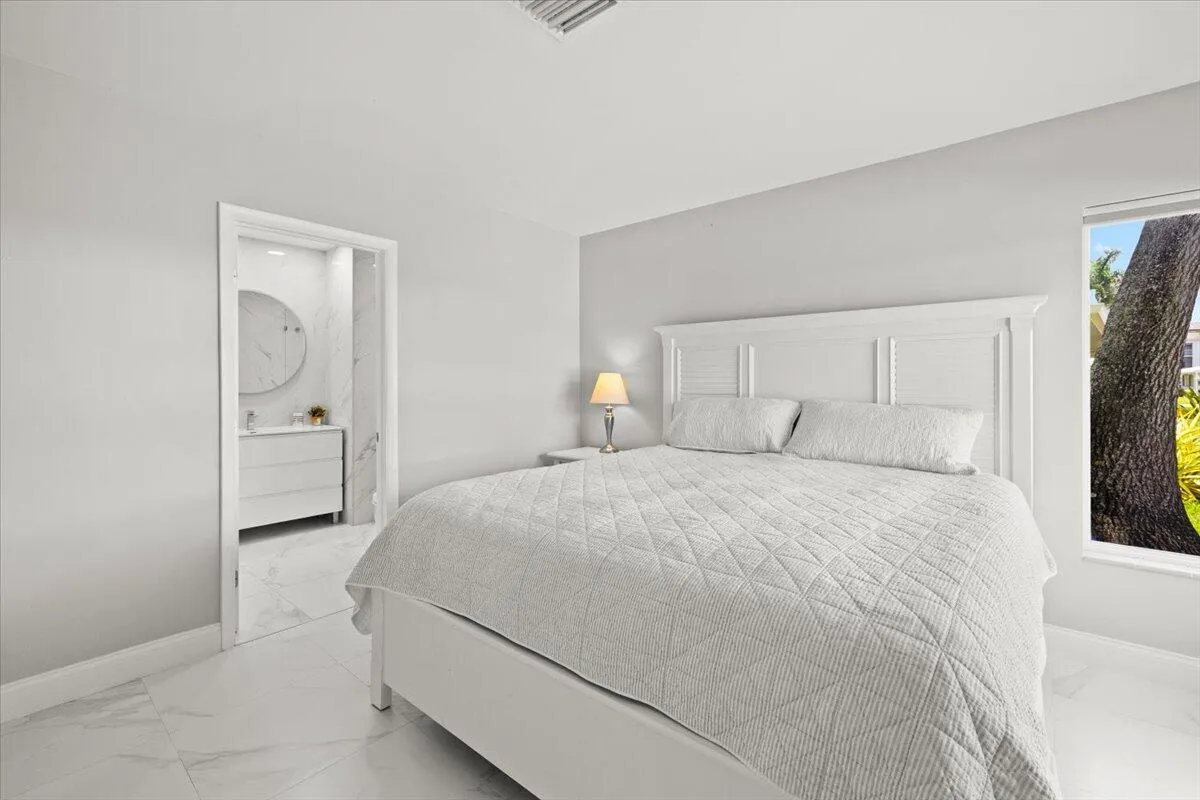 Bedroom featuring white tile flooring, neutral wall tones, and a window offering natural light