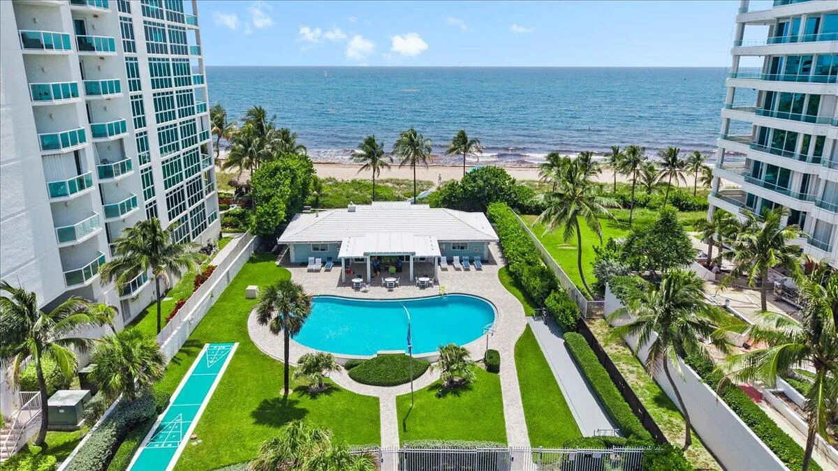 Resort-style amenities featuring an outdoor pool, shuffleboard court, and manicured green spaces