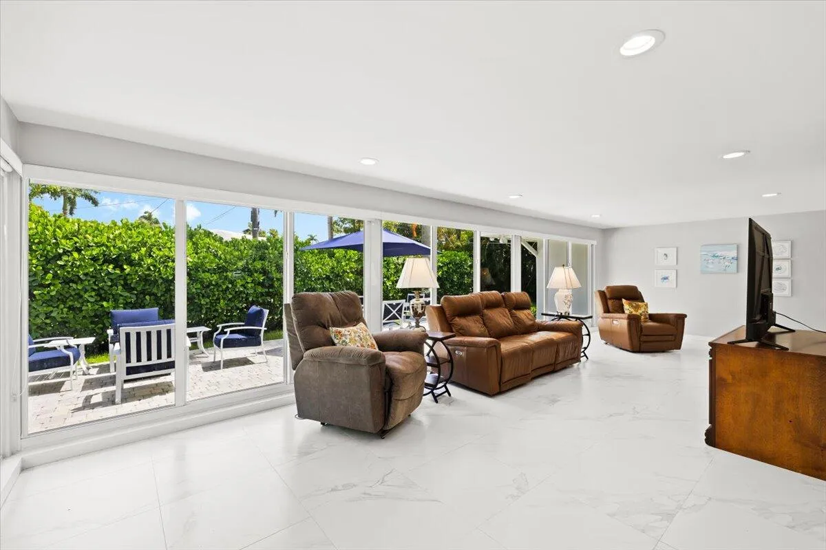 Living area featuring expansive floor-to-ceiling sliding glass doors, white tile flooring, recessed ceiling lighting, and light gray wall paint