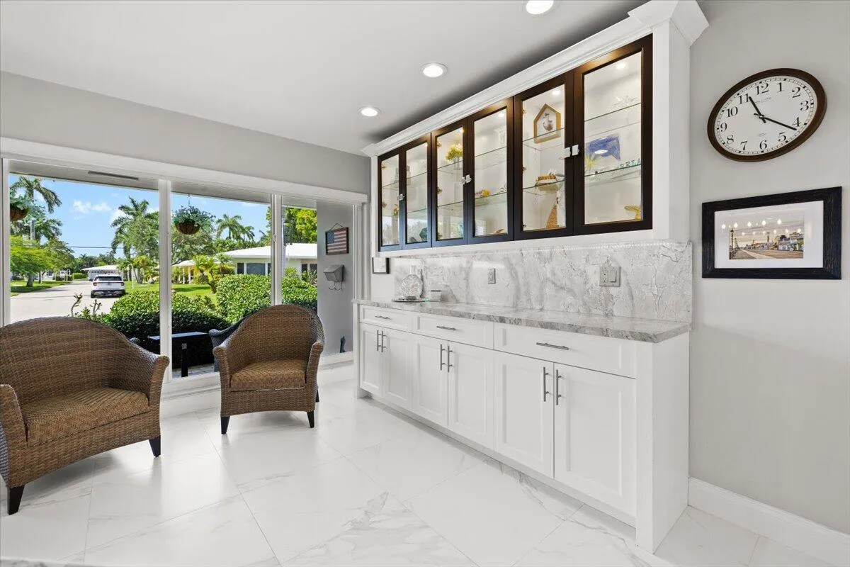 Integrated wet bar featuring white shaker-style cabinetry, a gray veined countertop, and a matching backsplash