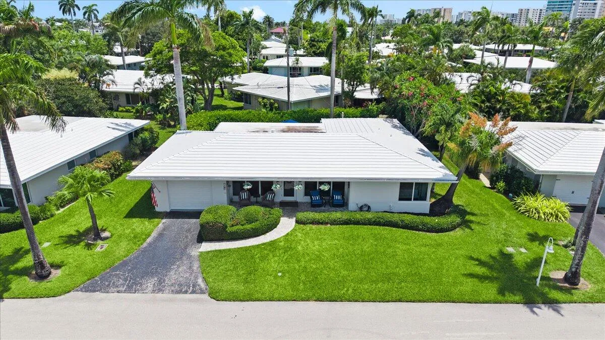 Single-story residence featuring a white tiled roof and a paved driveway