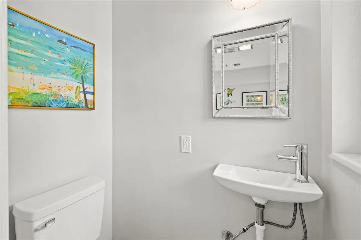 Wall-mounted corner sink with a polished chrome faucet, set against light gray walls