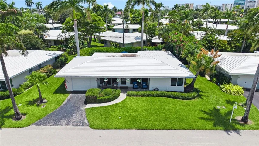 Single-story residence featuring a white tiled roof and a paved driveway