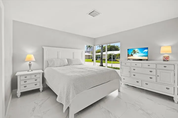 Spacious room featuring large windows, light gray wall tones, and white marble-look flooring