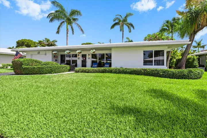 White exterior with a flat roofline, featuring a vibrant green lawn and manicured shrubbery