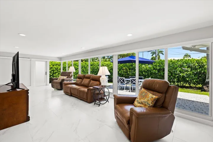 Spacious living area featuring large format white tile flooring and a wall of floor-to-ceiling windows