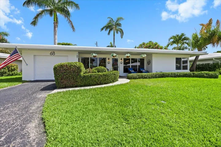 White stucco exterior with a flat roofline, featuring a single-car garage and a paved driveway