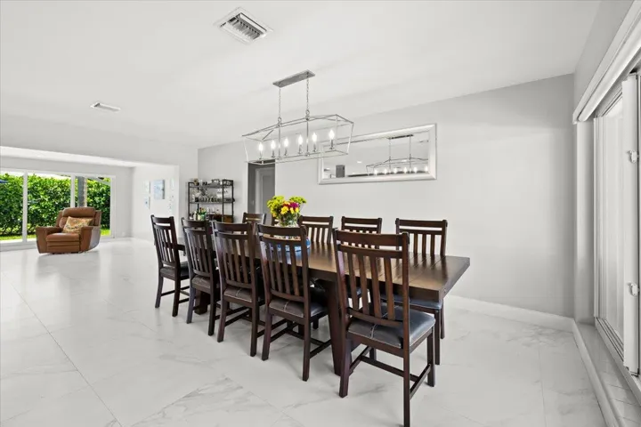 Spacious dining area featuring a rectangular dark wood table with seating for eight, illuminated by a linear chandelier