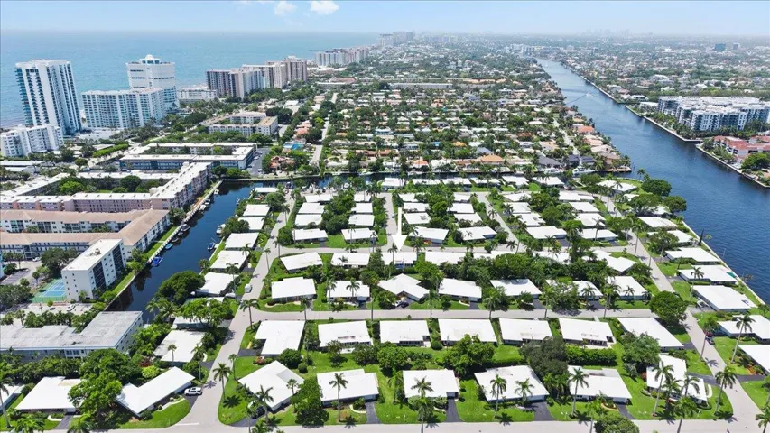 Coastal residential area featuring a grid layout of single-story properties with white roofs and mature landscaping
