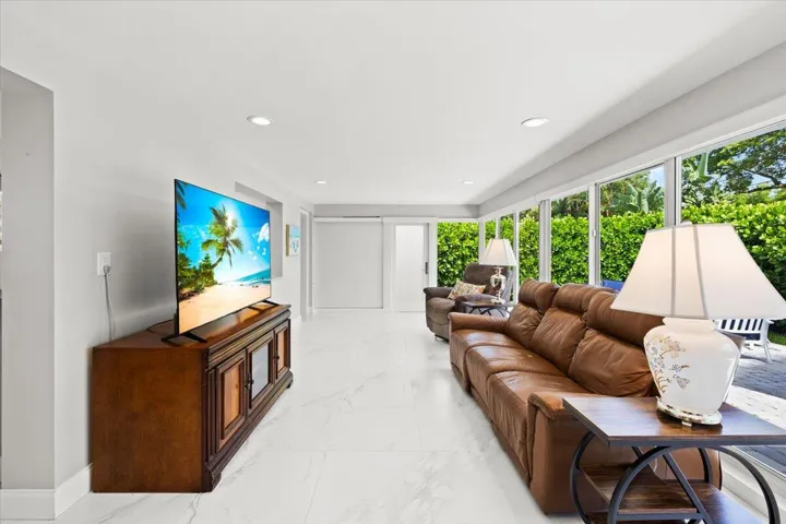 Spacious living area featuring light-toned flooring, recessed lighting, and a wall of windows
