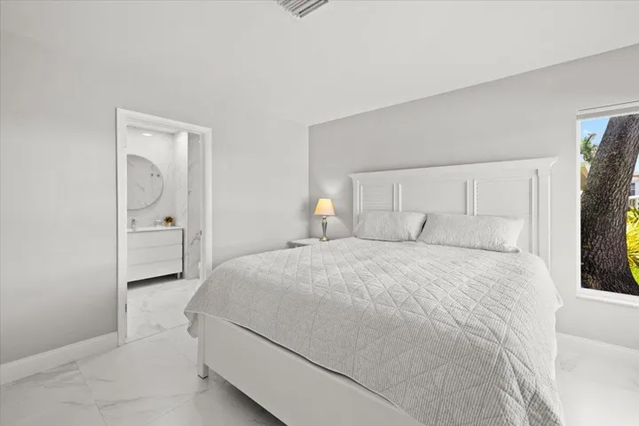 Bedroom featuring white tile flooring, neutral wall tones, and a window offering natural light