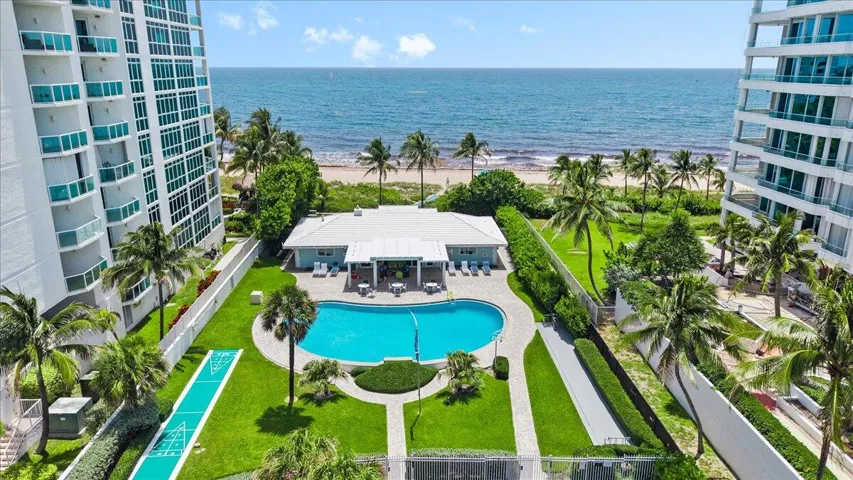 Resort-style amenities featuring an outdoor pool, shuffleboard court, and manicured green spaces