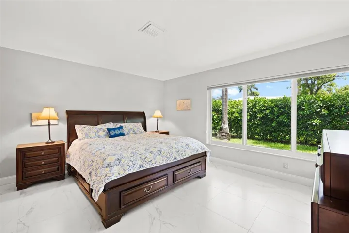 Spacious interior featuring large format tile flooring, light gray walls, and an expansive window overlooking mature landscaping