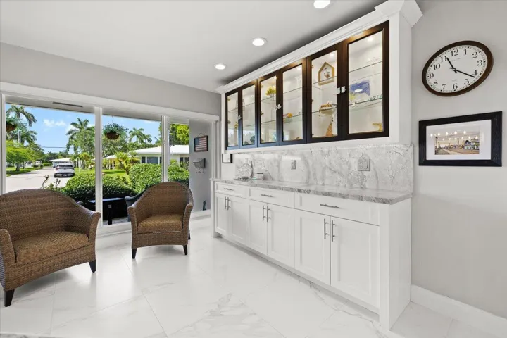 Integrated wet bar featuring white shaker-style cabinetry, a gray veined countertop, and a matching backsplash