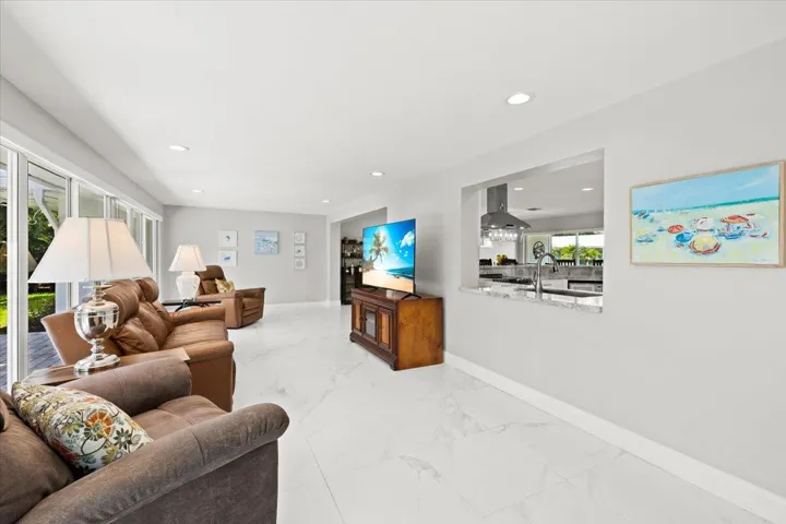 Spacious living area featuring white marble-look tile flooring, recessed lighting, and expansive glass doors opening to the outdoors