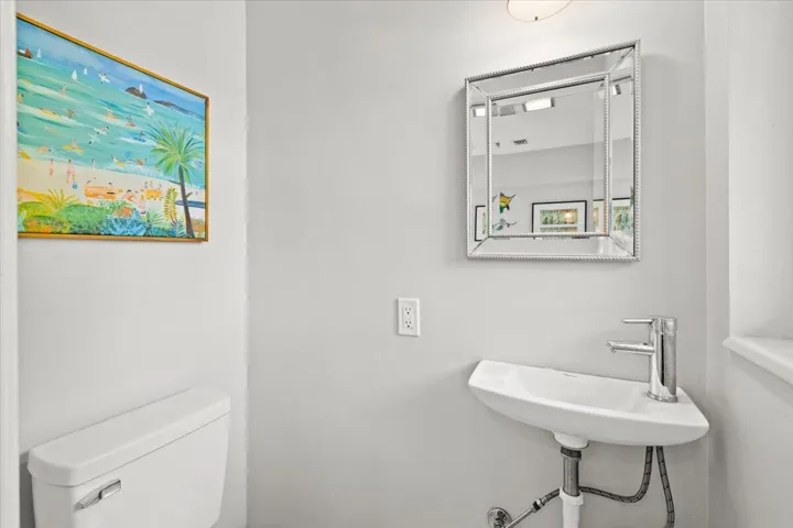 Wall-mounted corner sink with a polished chrome faucet, set against light gray walls