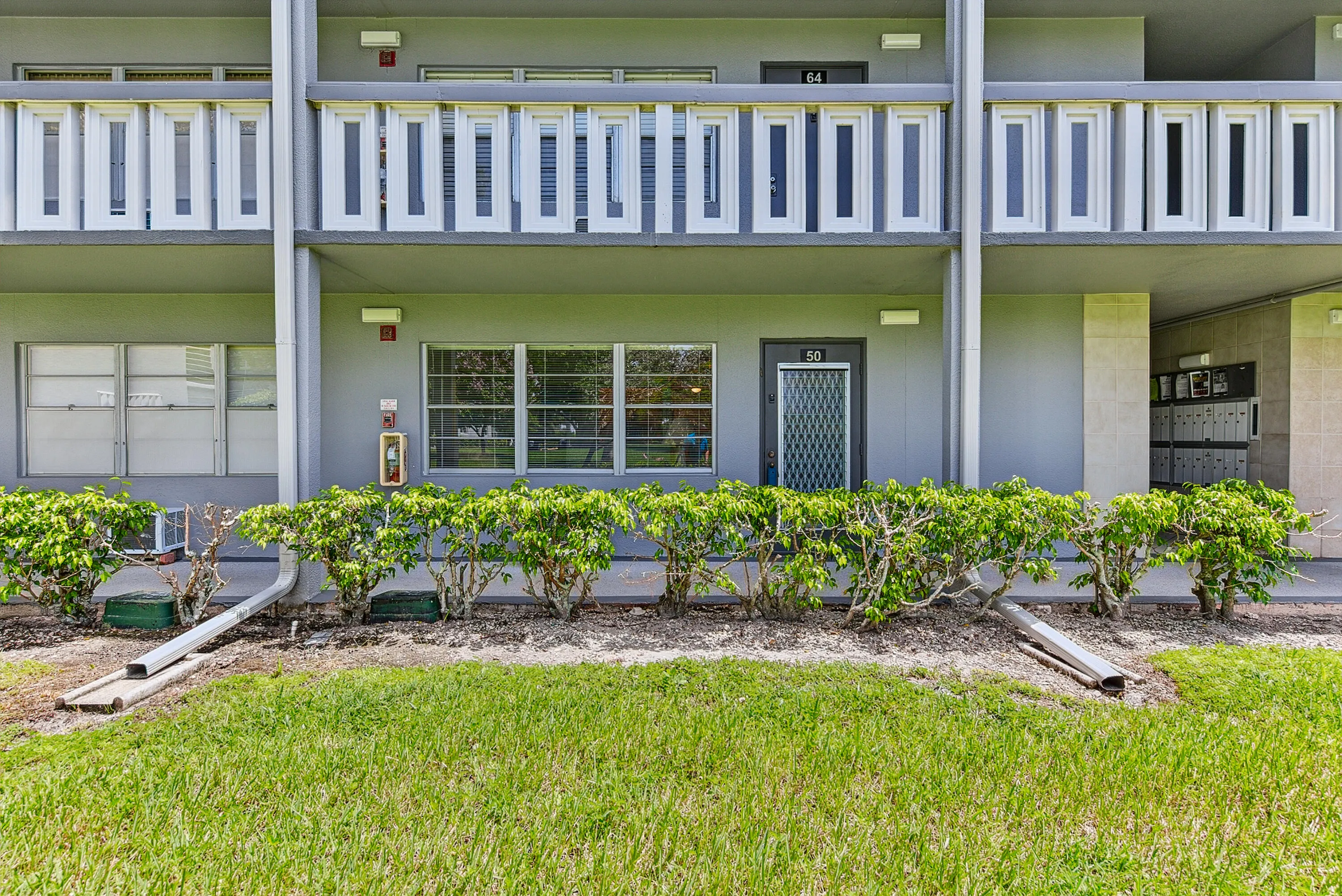 Ground floor unit entrance with a security screen door, multiple windows, and exterior lighting