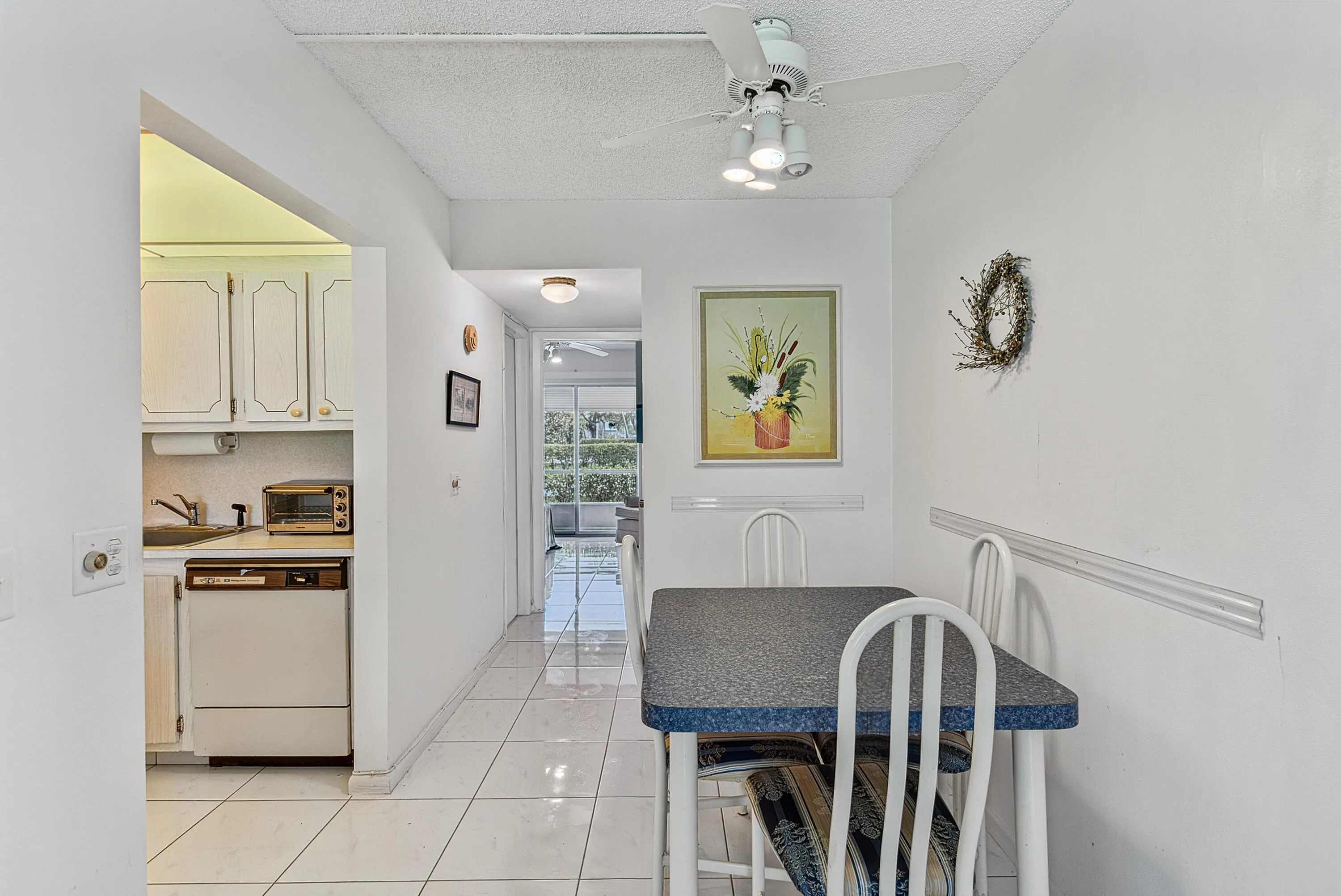 Dining area featuring tile flooring, a textured ceiling, a ceiling fan with integrated lighting, and a white chair rail molding