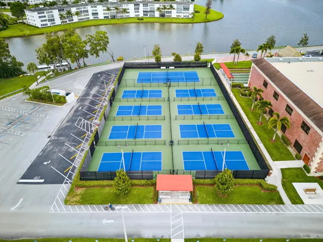Eight pickleball courts with blue playing surfaces and green surrounds