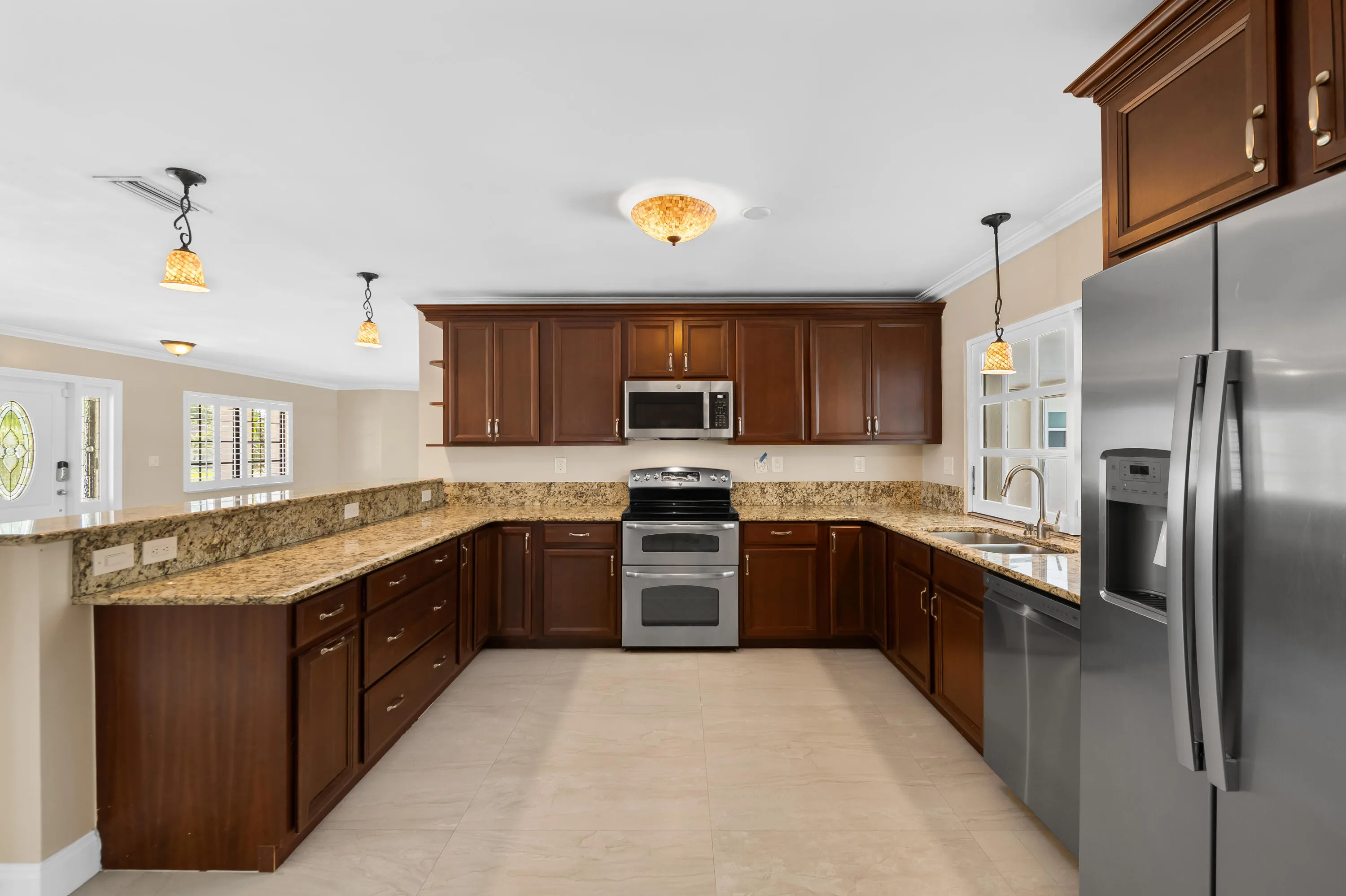 Kitchen featuring wood cabinetry, light-toned stone countertops, stainless steel appliances, and tile flooring