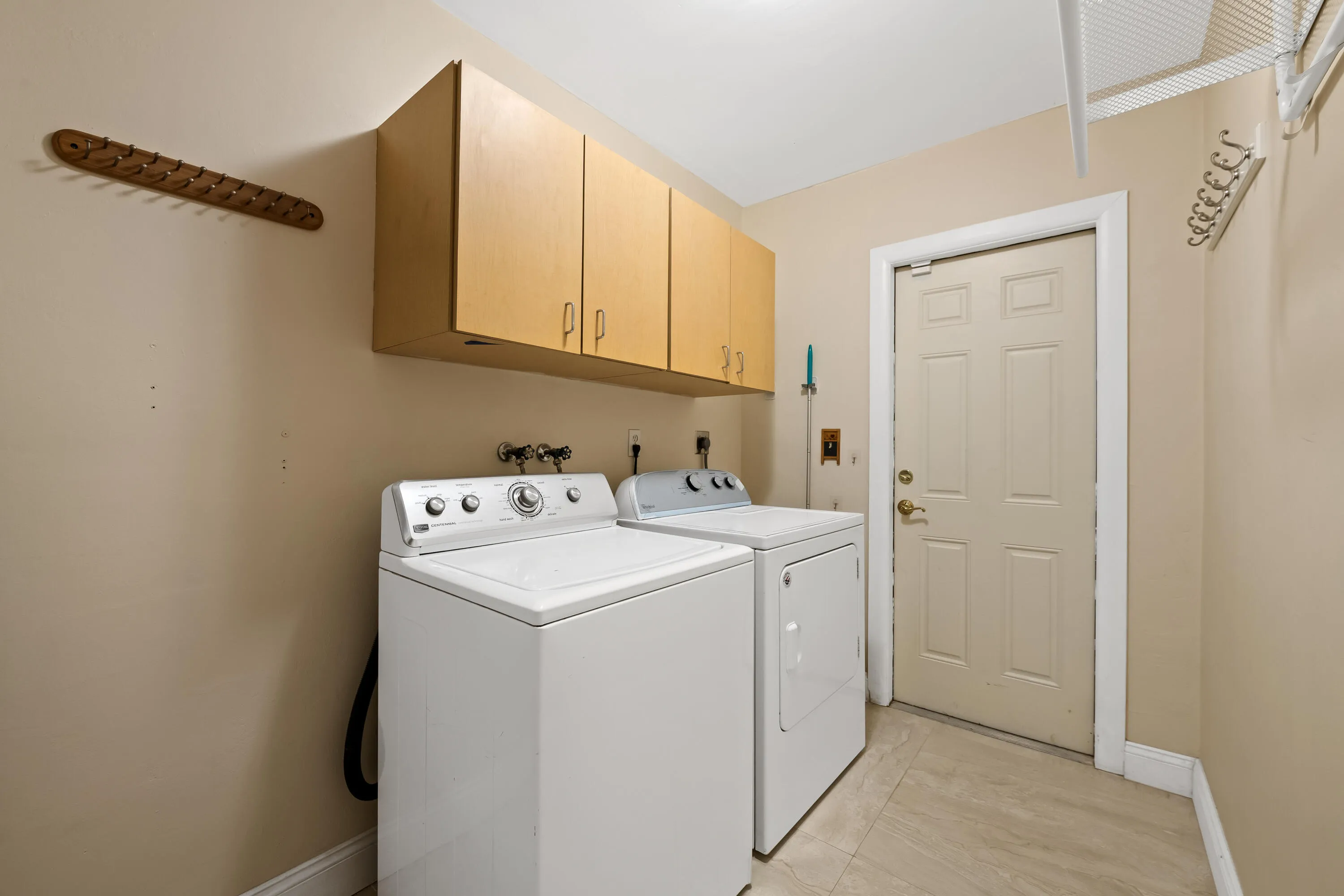 Dedicated laundry space featuring upper cabinetry, a utility door.