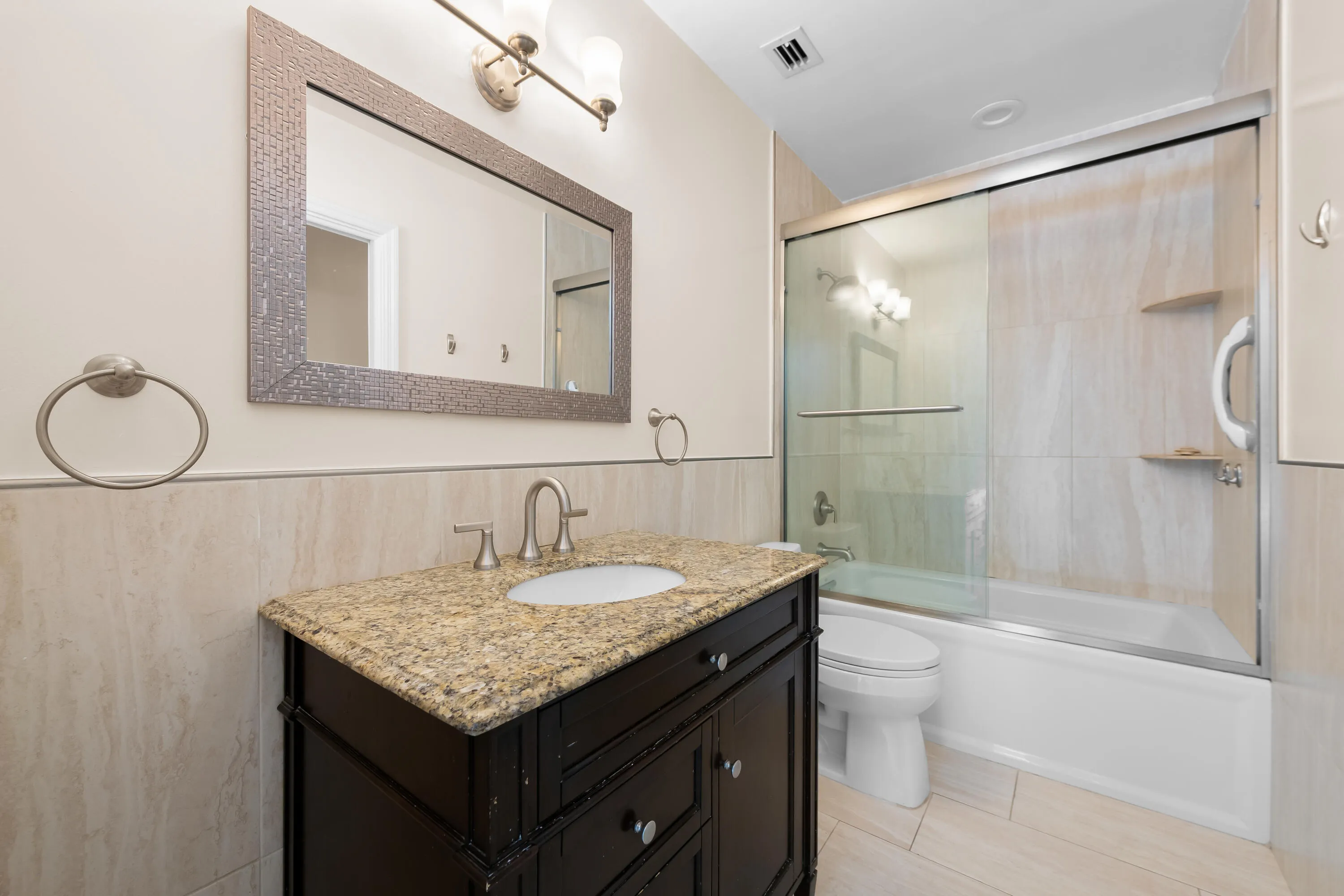 Bathroom featuring a dark wood vanity with a granite countertop and undermount sink. Tub/Shower.