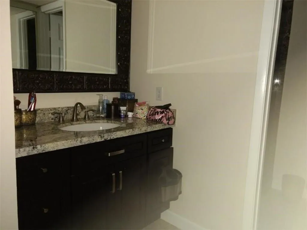Vanity with a light-colored granite countertop, an undermount sink, and a brushed nickel faucet