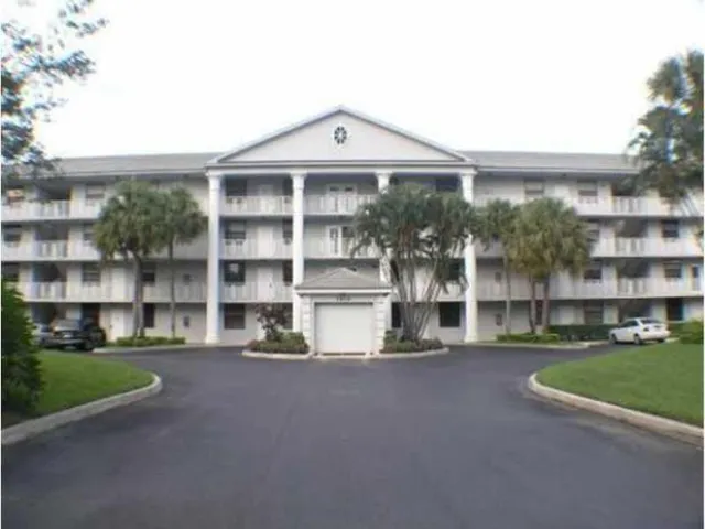 Three-story multi-unit structure featuring a classical architectural facade, multiple balconies, and a central portico with columns
