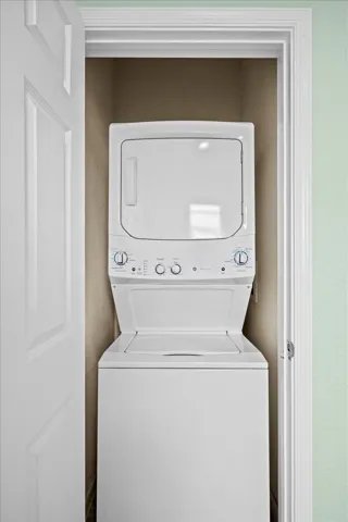 Dedicated laundry closet featuring a white stacked washer and dryer unit