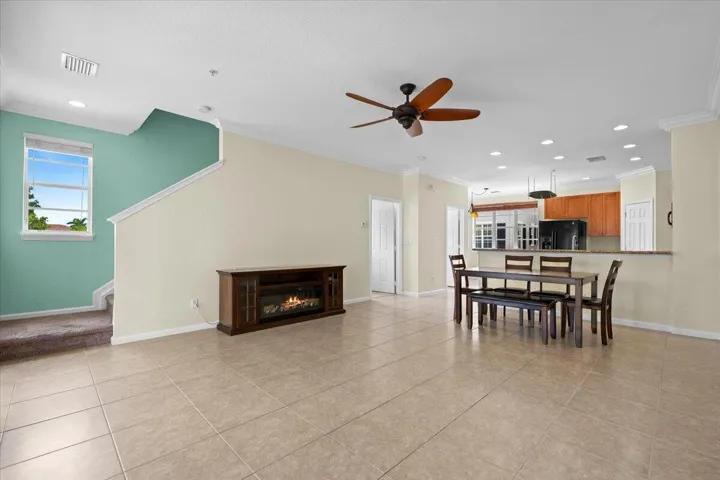 Spacious living area featuring neutral tile flooring and crown molding