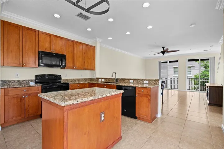 Open-concept kitchen featuring wood cabinetry, granite countertops, and a central island with additional counter space