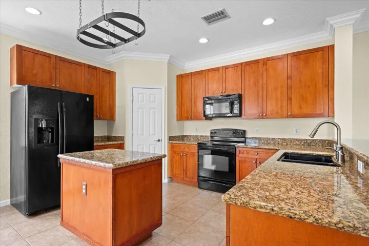 Kitchen featuring warm wood cabinetry, granite countertops, and a black appliance suite