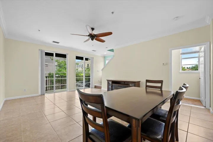 Spacious living area featuring tile flooring, crown molding, and a ceiling fan