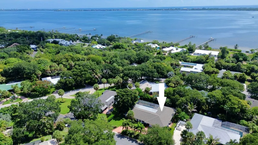 Waterfront community property featuring lush landscaping, mature trees, and a visible body of water with docks