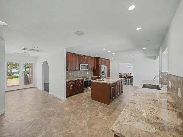 Expansive kitchen featuring a large island, generous countertop space, rich wood cabinetry, stainless steel appliances, and recessed lighting