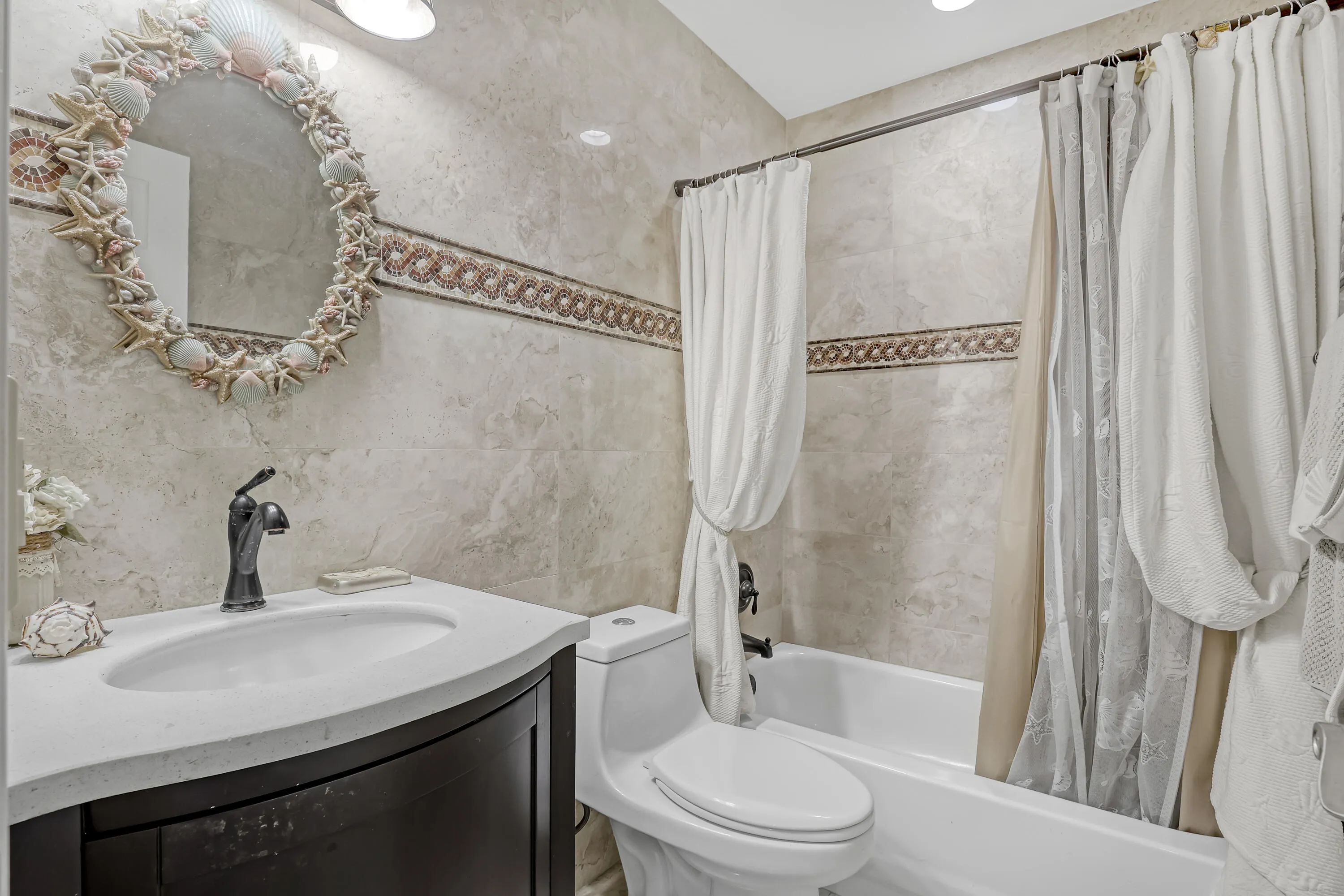 Bathroom featuring a curved vanity with an integrated sink, dark bronze faucet, and a tiled shower-tub combination