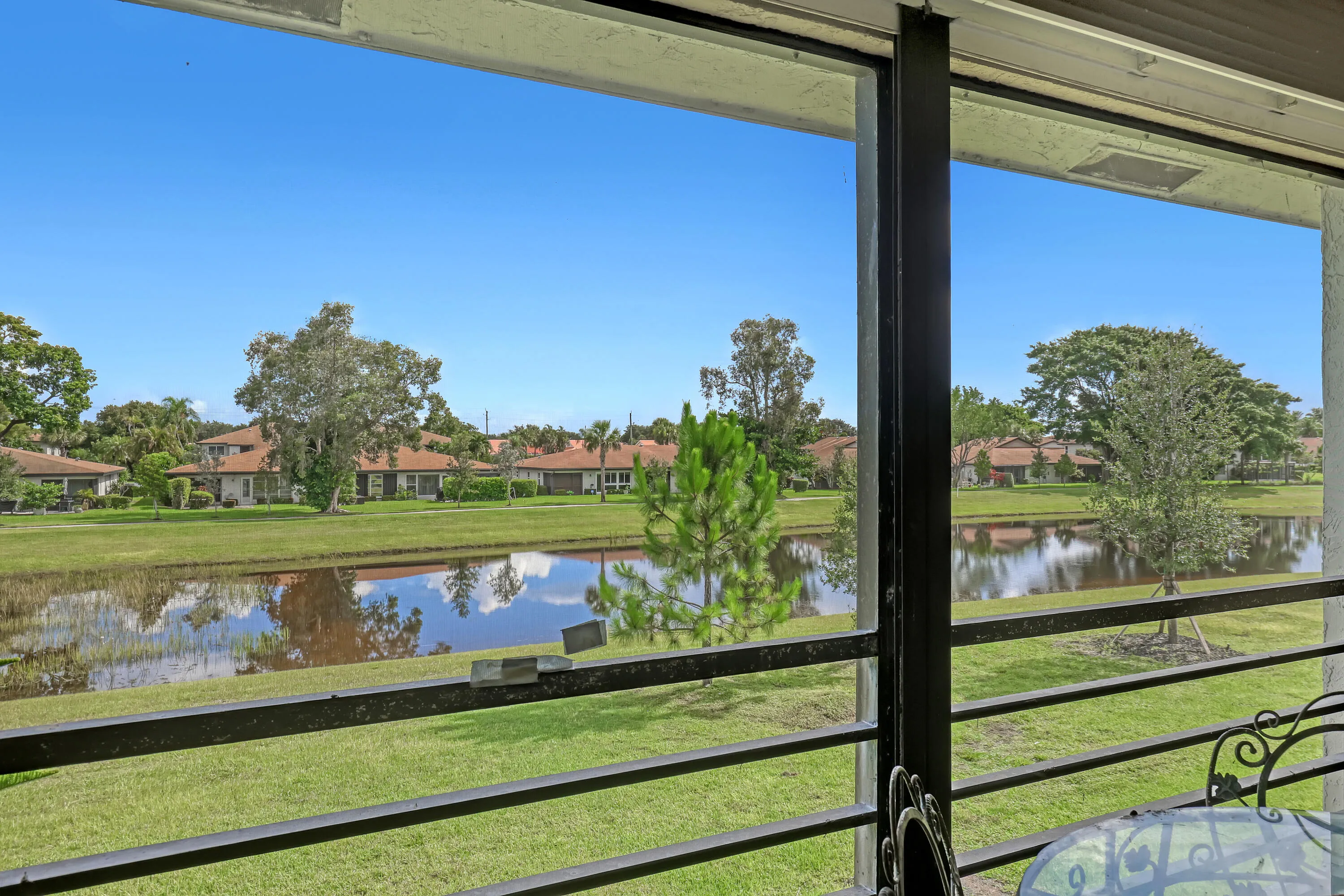 Screened outdoor area offering panoramic pond and green space views