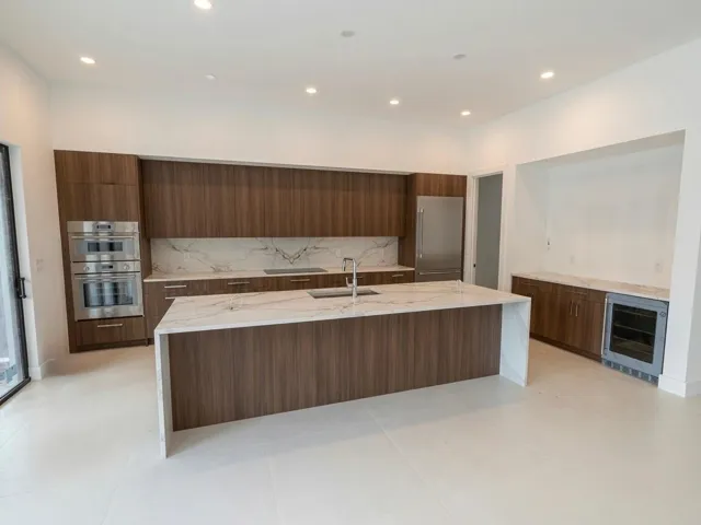 Massive kitchen with Thermador applilances. Bar area will be completed with matching wood open shelving and a tinted mirror backsplash.