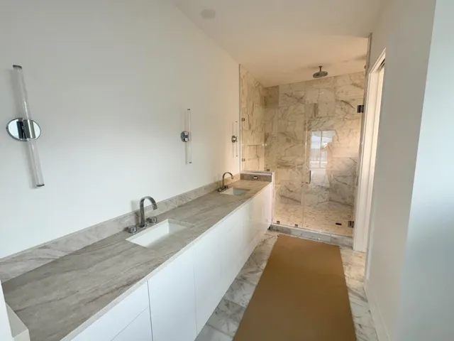Main bathroom with marble flooring and walls along with Taj Mahal countertop and Kohler fixtures.