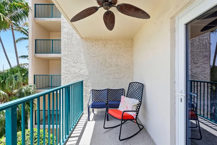 Private outdoor balcony featuring a textured stucco finish, a ceiling fan with wood-finish blades, a white sliding glass door, and a teal railing