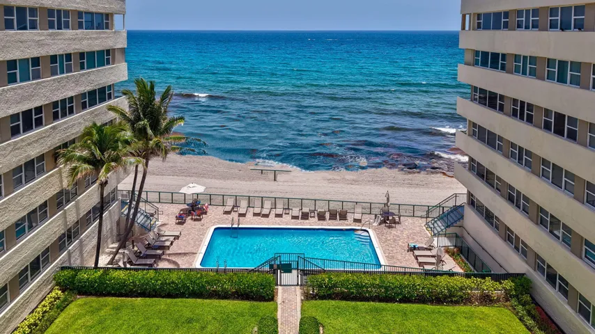 Oceanfront building featuring a private swimming pool, direct beach access, and mature palm trees