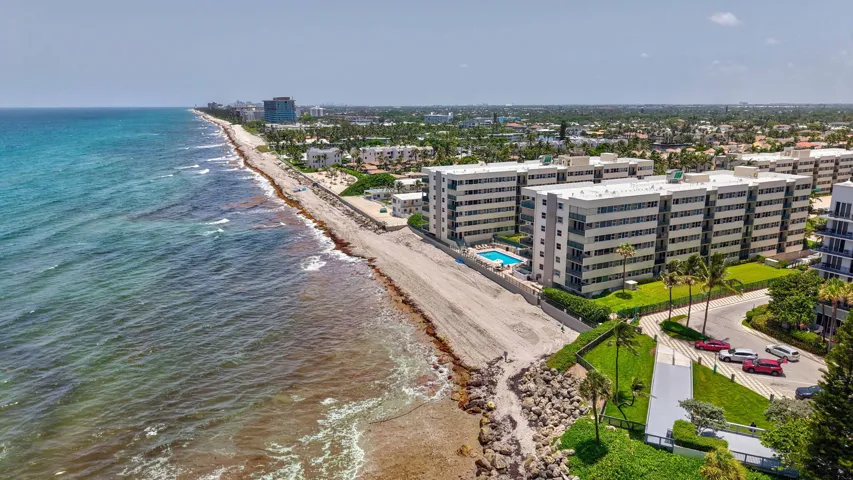 Coastal property featuring oceanfront access, multiple building structures, a resort-style swimming pool, and established tropical landscaping