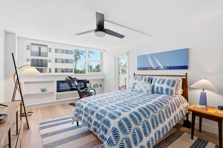 Bright bedroom featuring light wood look flooring, a contemporary ceiling fan, and a built-in shelving unit with a fireplace