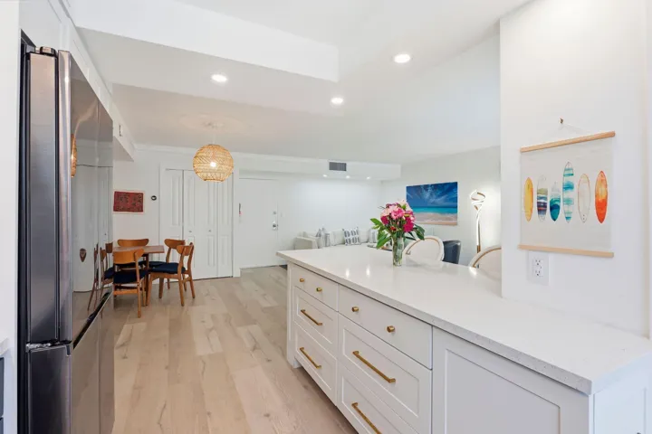 Kitchen island with a light-toned countertop, white cabinetry, and gold-toned hardware
