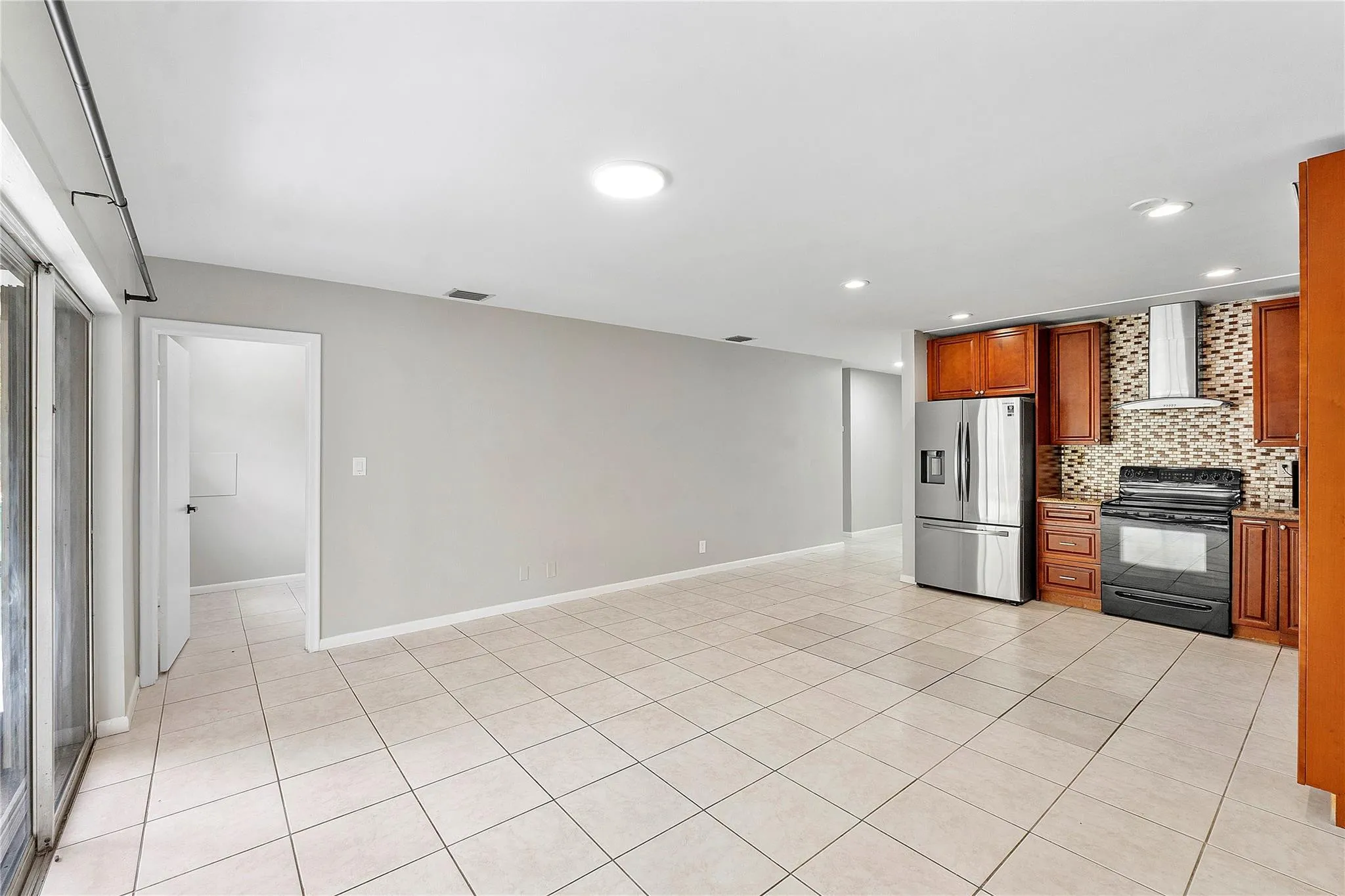 Open-concept living area featuring light-toned tile flooring and recessed lighting