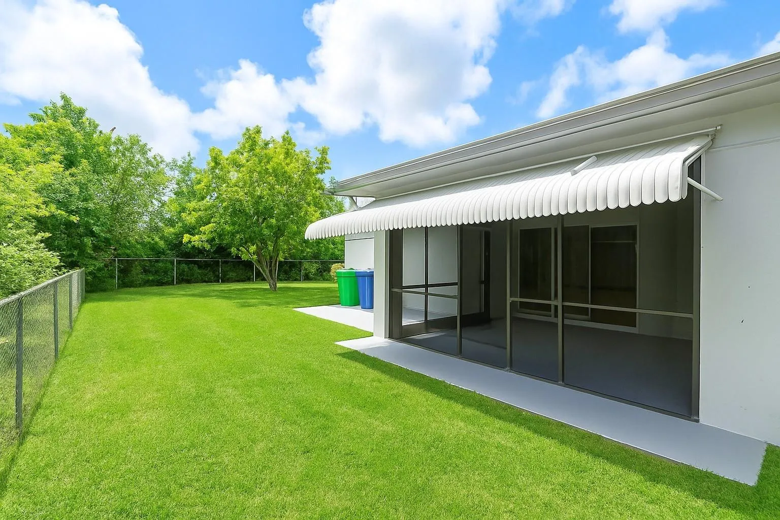 Expansive green lawn with a chain-link fence and mature perimeter landscaping